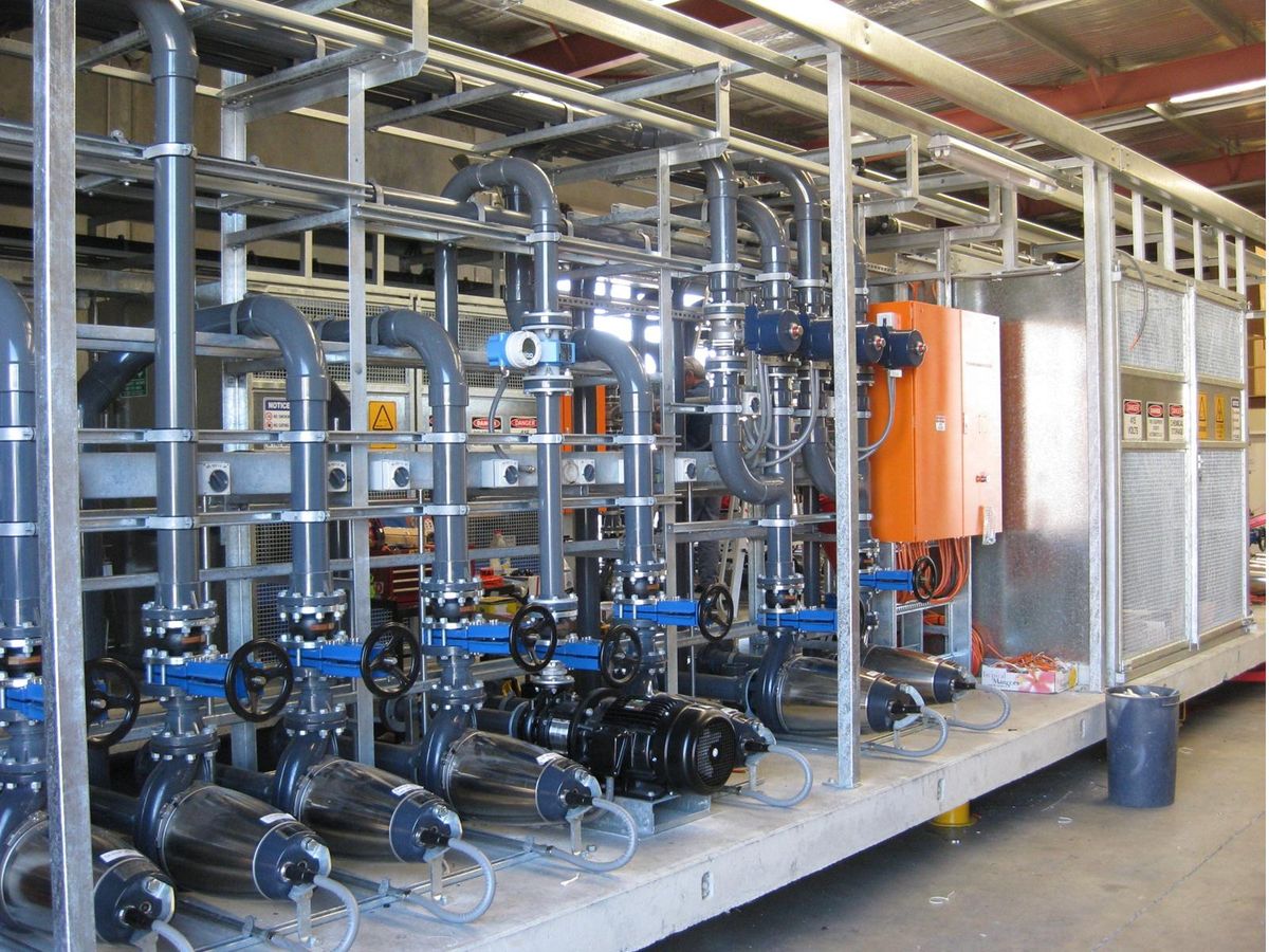 A bank of pumps, valves and UPVC pipework on a galvanised skid, with its control panel, in the workshop.